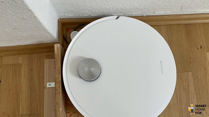 Der Dreame Aqua10 reinigt eine Ecke mit ausgefahrener Seitenbürste.
